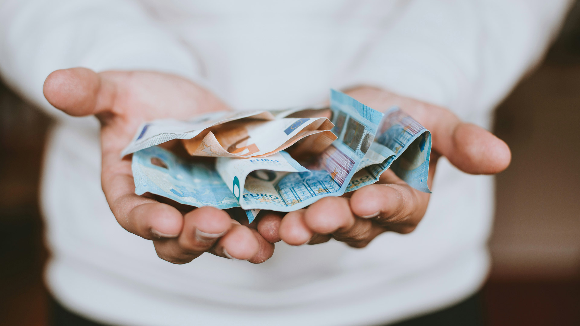 Person hält Geldscheine – Bestattungskosten und finanzielle Planung