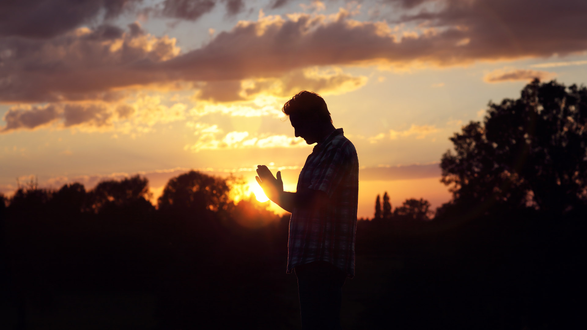 Person in stiller Andacht vor Sonnenuntergang – Symbol für Abschied und Trauer